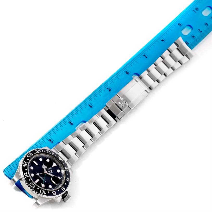 The image shows the Rolex GMT-Master 116710 Men's Stainless Steel Black Dial 116710 Men's Stainless Steel Black Dial watch lying flat with its dial, bracelet, and clasp visible, next to a blue ruler for measurement.