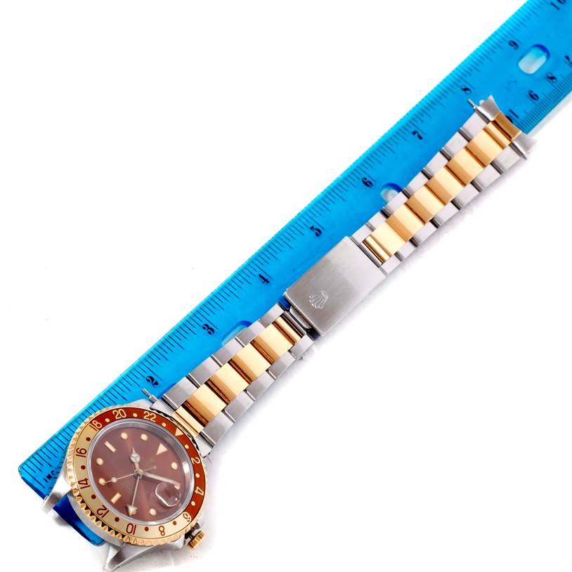 This top-down image shows a Rolex GMT-Master 16713 Men's Stainless Steel Brown Dial 16713 Men's Stainless Steel Brown Dial watch with its bracelet laid next to a blue ruler for measurement.