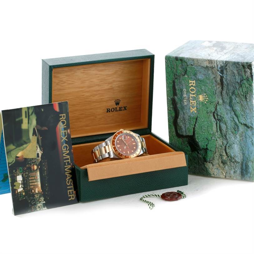 The image shows a Rolex GMT-Master 16713 Men's Stainless Steel Brown Dial 16713 Men's Stainless Steel Brown Dial watch inside its open green box with outer packaging and a manual.