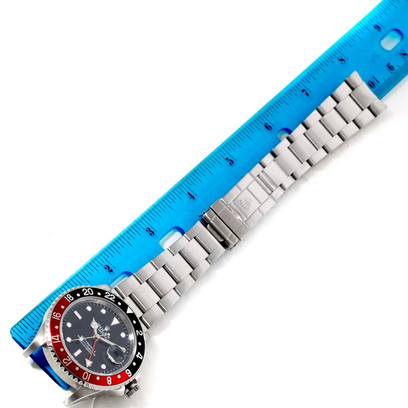 The image shows a Rolex GMT-Master 16710 Men
s Stainless Steel Black Dial 16710 Men
s Stainless Steel Black Dial watch lying flat with a blue ruler measuring its length.