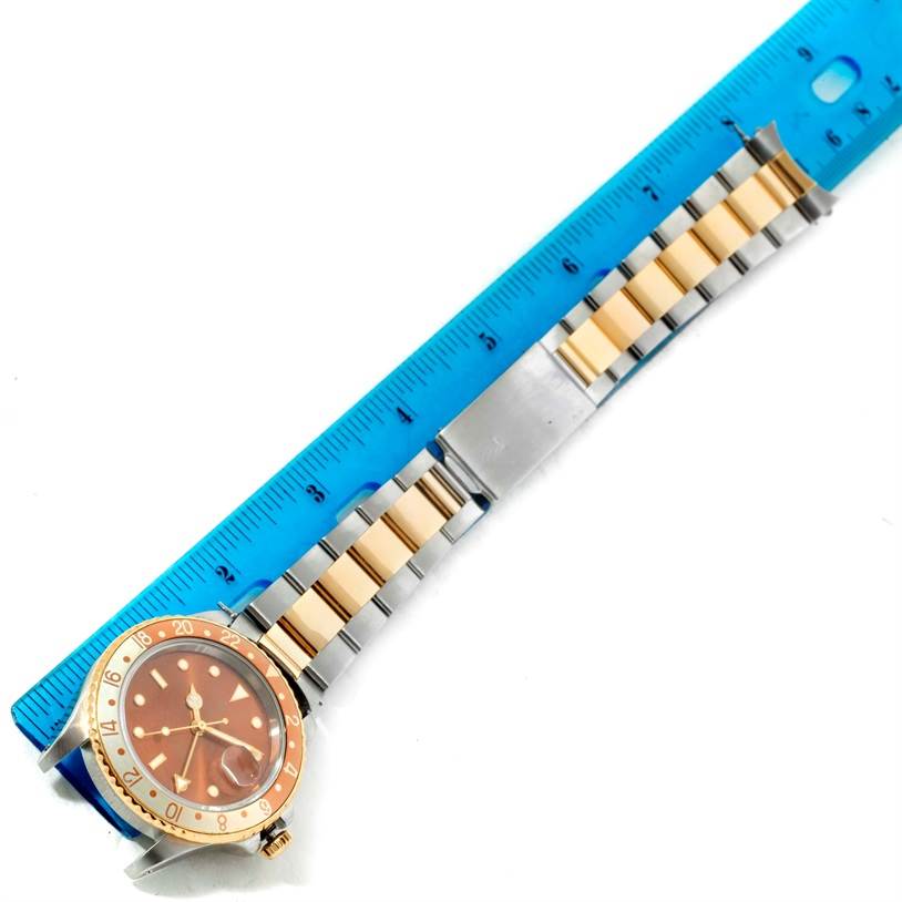 The image shows a top-down view of a Rolex GMT-Master 16713 Men's Stainless Steel Brown Dial 16713 Men's Stainless Steel Brown Dial watch with a blue ruler measuring its bracelet.