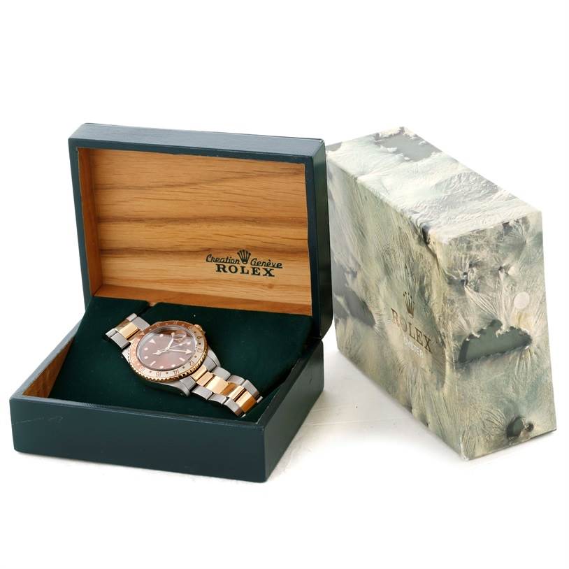 The Rolex GMT-Master 16713 Men's Stainless Steel Brown Dial 16713 Men's Stainless Steel Brown Dial watch is displayed in an open, branded wooden box with an additional outer box beside it.