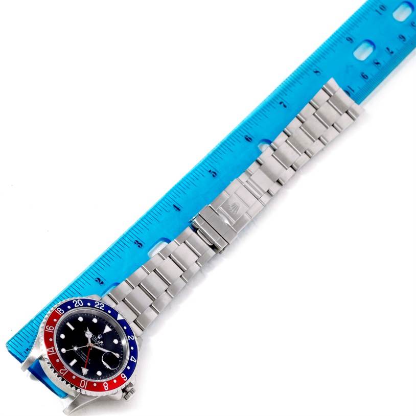 The image shows a top-down view of a Rolex GMT-Master 16710 Men's Stainless Steel Black Dial 16710 Men's Stainless Steel Black Dial watch alongside a blue ruler for scale.