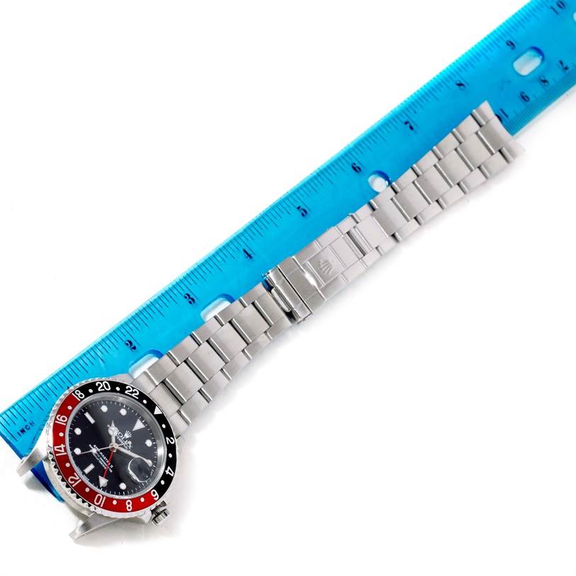 The image shows a top view of a Rolex GMT-Master 16710 Men's Stainless Steel Black Dial 16710 Men's Stainless Steel Black Dial watch with a stainless steel bracelet laid next to a blue ruler.