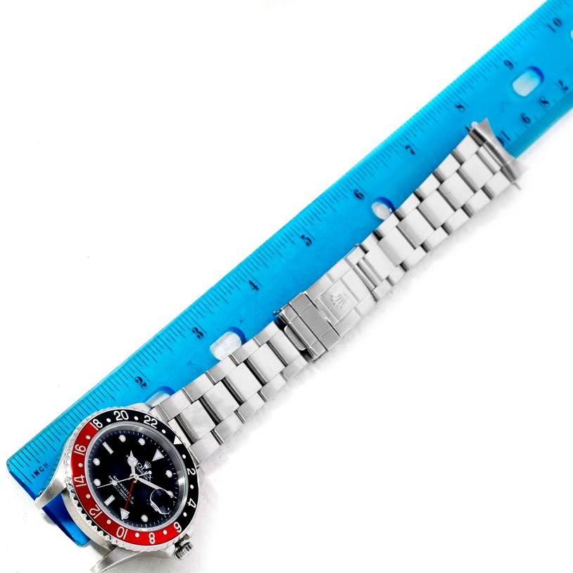 The image shows a top view of a Rolex GMT-Master 16710 Men's Stainless Steel Black Dial 16710 Men's Stainless Steel Black Dial watch with its bracelet placed next to a blue ruler.