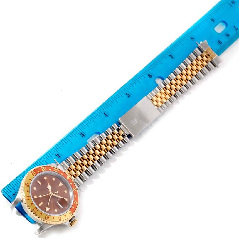 The image shows a top-down view of a Rolex GMT-Master 16713 Men's Stainless Steel Brown Dial 16713 Men's Stainless Steel Brown Dial watch including its face, bezel, and bracelet placed against a ruler.