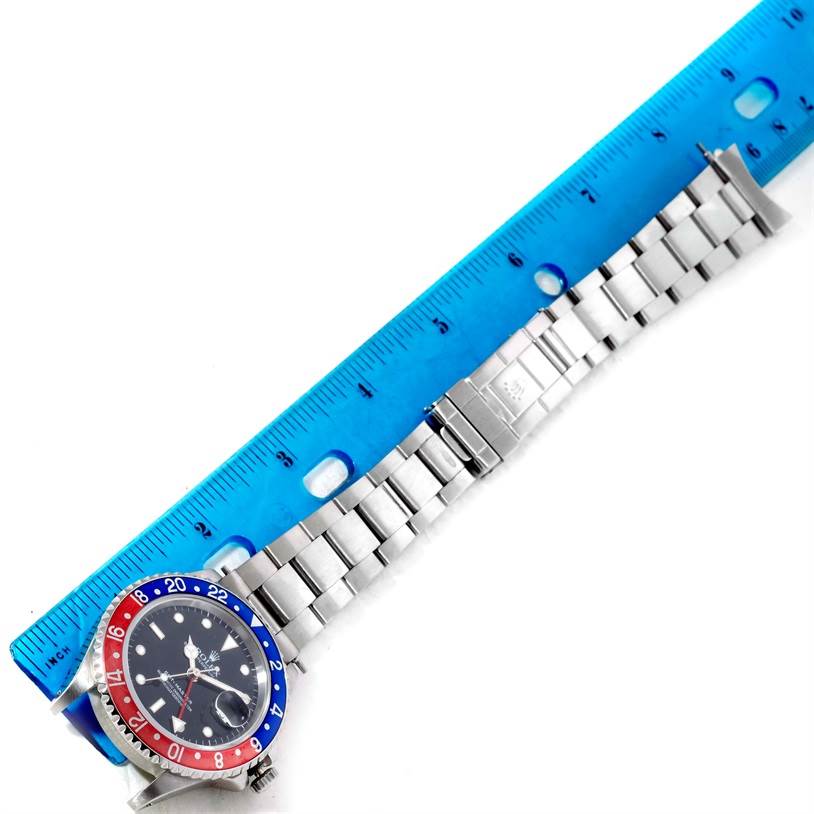 The Rolex GMT-Master 16700 Men's Stainless Steel Black Dial 16700 Men's Stainless Steel Black Dial watch is shown horizontally, with its bracelet extended alongside a ruler for measurement.