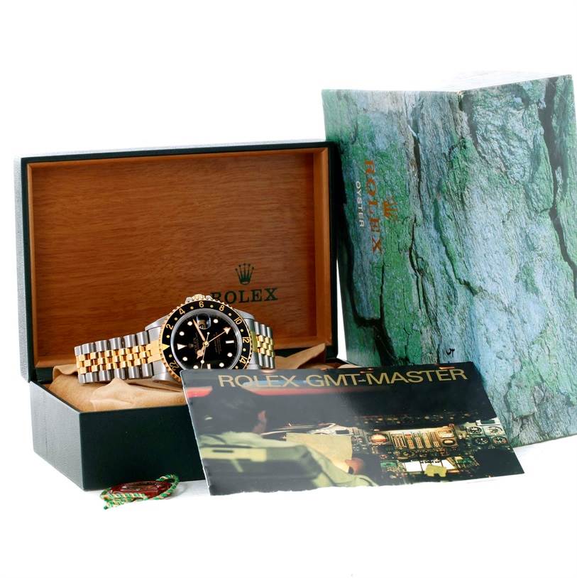 The Rolex GMT-Master 16713 Men
s Stainless Steel Black Dial 16713 Men
s Stainless Steel Black Dial watch is displayed at a slight angle inside its open box, accompanied by its packaging and booklet.