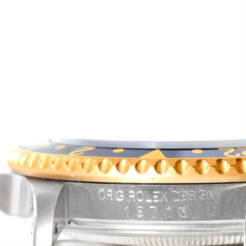 The image shows a close-up of the bezel and part of the case of the Rolex GMT-Master 16713 Men
s Stainless Steel Black Dial 16713 Men
s Stainless Steel Black Dial watch, highlighting the "ORIG ROLEX DESIGN" engraving.