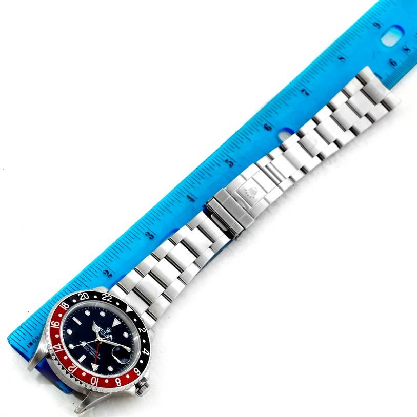 The Rolex GMT-Master 16710 Men's Stainless Steel Black Dial 16710 Men's Stainless Steel Black Dial watch is shown from a top-down angle with the face, bezel, and bracelet visible next to a ruler.