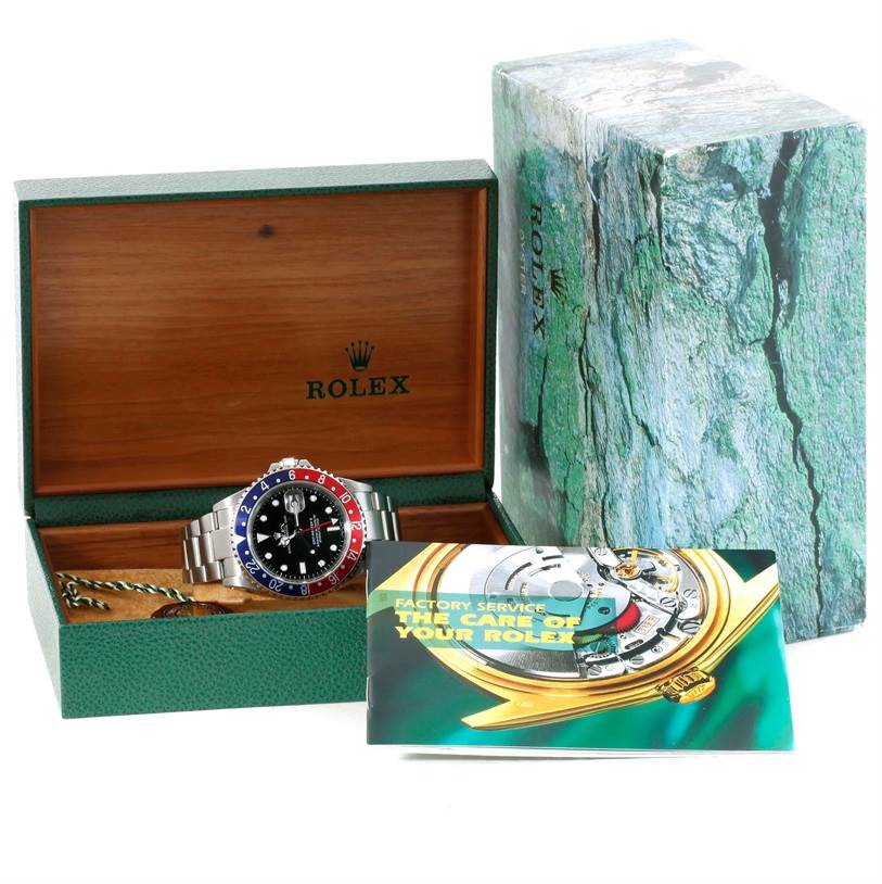 The image shows a Rolex GMT-Master 16710 Men
s Stainless Steel Black Dial 16710 Men
s Stainless Steel Black Dial watch in its open presentation box, with the outer box and a factory service manual also visible.