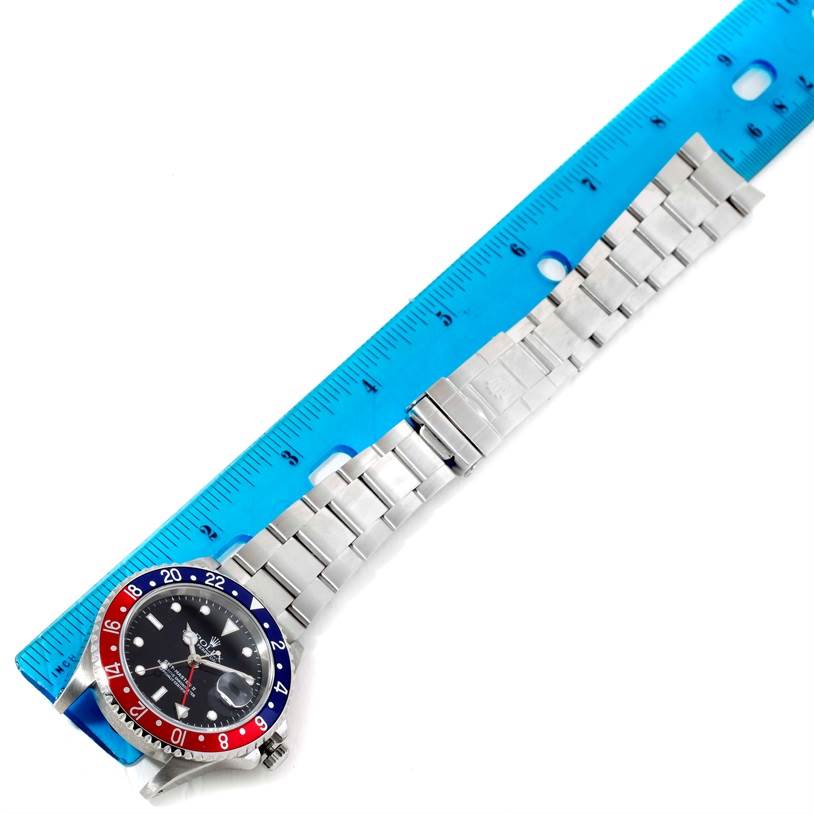 The image shows the Rolex GMT-Master 16710 Men
s Stainless Steel Black Dial 16710 Men
s Stainless Steel Black Dial watch laid flat with a ruler for scale, highlighting the bezel, dial, and bracelet.