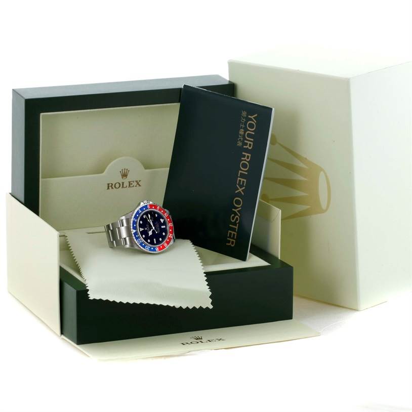 The Rolex GMT-Master 16710 Men's Stainless Steel Black Dial 16710 Men's Stainless Steel Black Dial watch is shown in its open box, accompanied by a booklet and cleaning cloth.