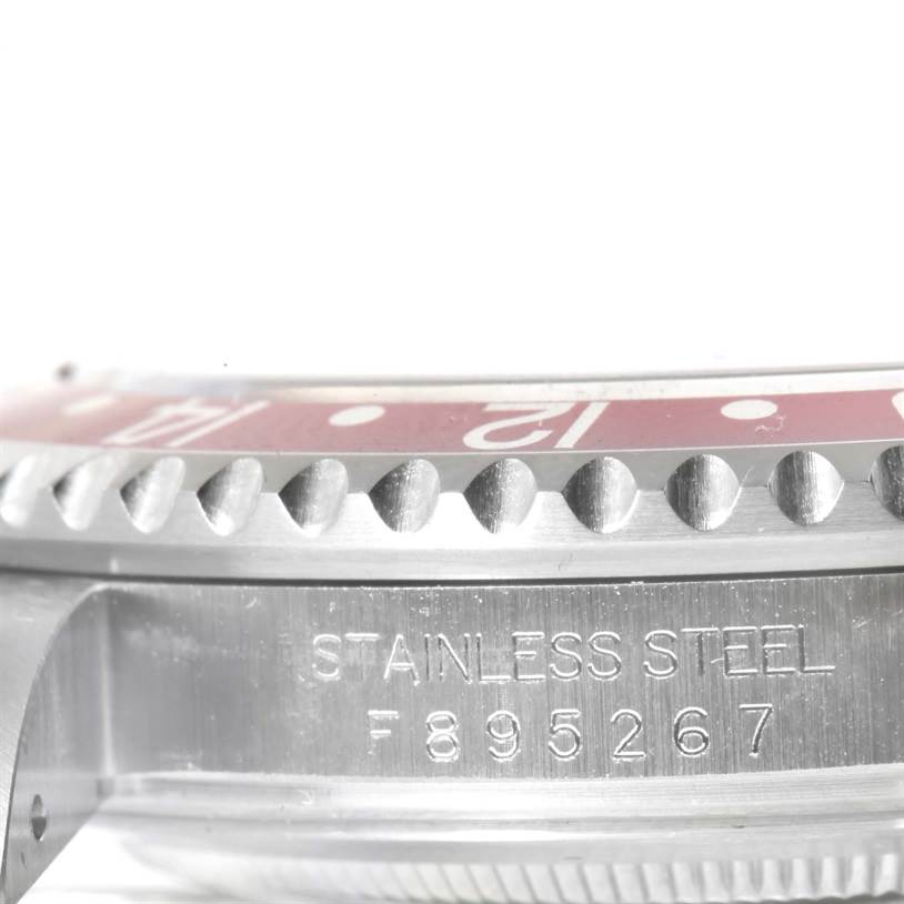 This image shows a close-up of the stainless steel case and bezel of a Rolex GMT-Master 16710 Men's Stainless Steel Black Dial 16710 Men's Stainless Steel Black Dial watch, with the serial number engraved.