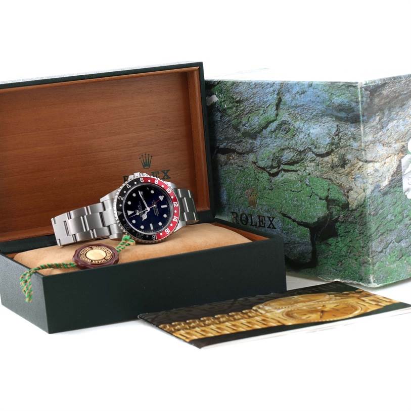 The image shows a Rolex GMT-Master 16710 Men's Stainless Steel Black Dial 16710 Men's Stainless Steel Black Dial watch displayed in an open box with accompanying manuals and a tag.
