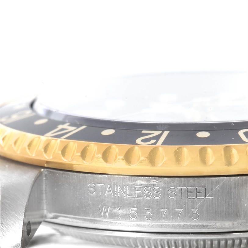 This image shows a close-up of the Rolex GMT-Master 16713 Men
s Stainless Steel Black Dial 16713 Men
s Stainless Steel Black Dial watch, focusing on the bezel and part of the stainless steel case with the serial number.