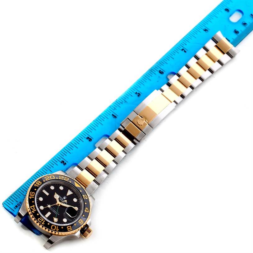 This image shows a Rolex GMT-Master 116713LN Men's Stainless Steel Black Dial 116713LN Men's Stainless Steel Black Dial watch laid flat with a blue ruler beside it, displaying the watch face, bezel, and metal bracelet.