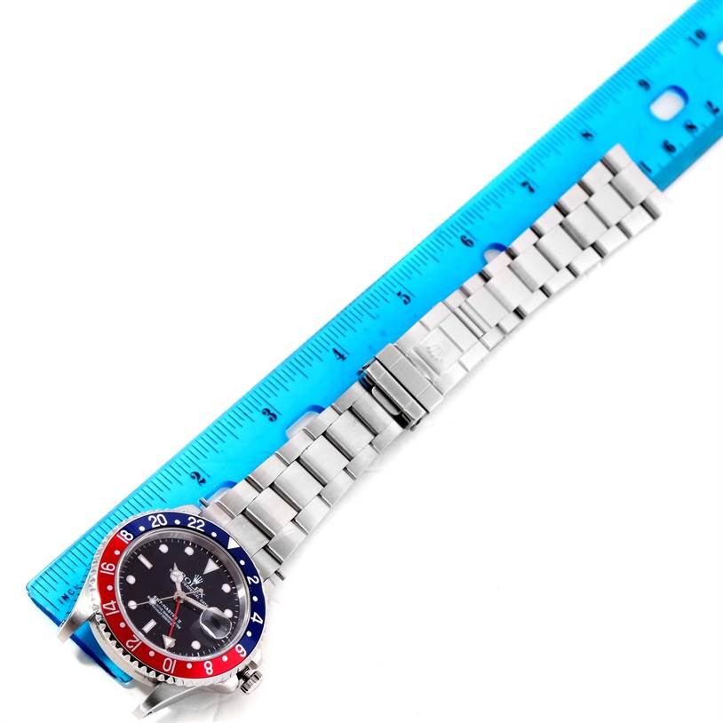 The image shows a Rolex GMT-Master 16710 Men's Stainless Steel Black Dial 16710 Men's Stainless Steel Black Dial watch laying flat with its metal bracelet and clasp, next to a blue ruler for scale.