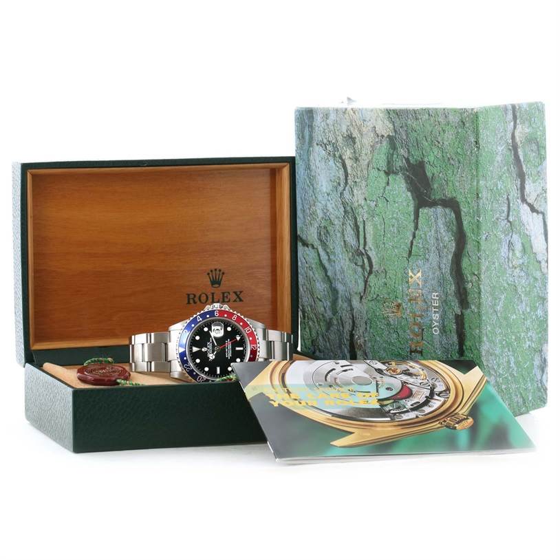 This image shows a Rolex GMT-Master 16710 Men's Stainless Steel Black Dial 16710 Men's Stainless Steel Black Dial watch in its open box, along with its warranty card and service manual.