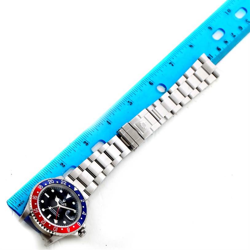 The image shows the Rolex GMT-Master 16710 Men's Stainless Steel Black Dial 16710 Men's Stainless Steel Black Dial watch displayed flat with its bracelet extended and a blue ruler next to it.