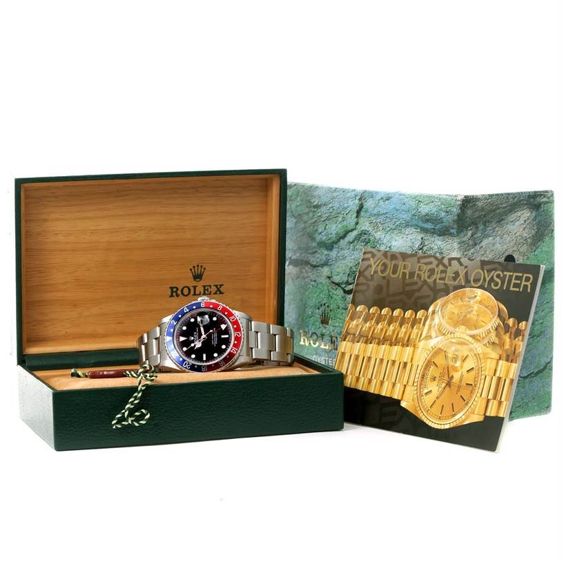 The image shows a Rolex GMT-Master 16700 Men's Stainless Steel Black Dial 16700 Men's Stainless Steel Black Dial watch in its open box, with brochures and accessories beside it.