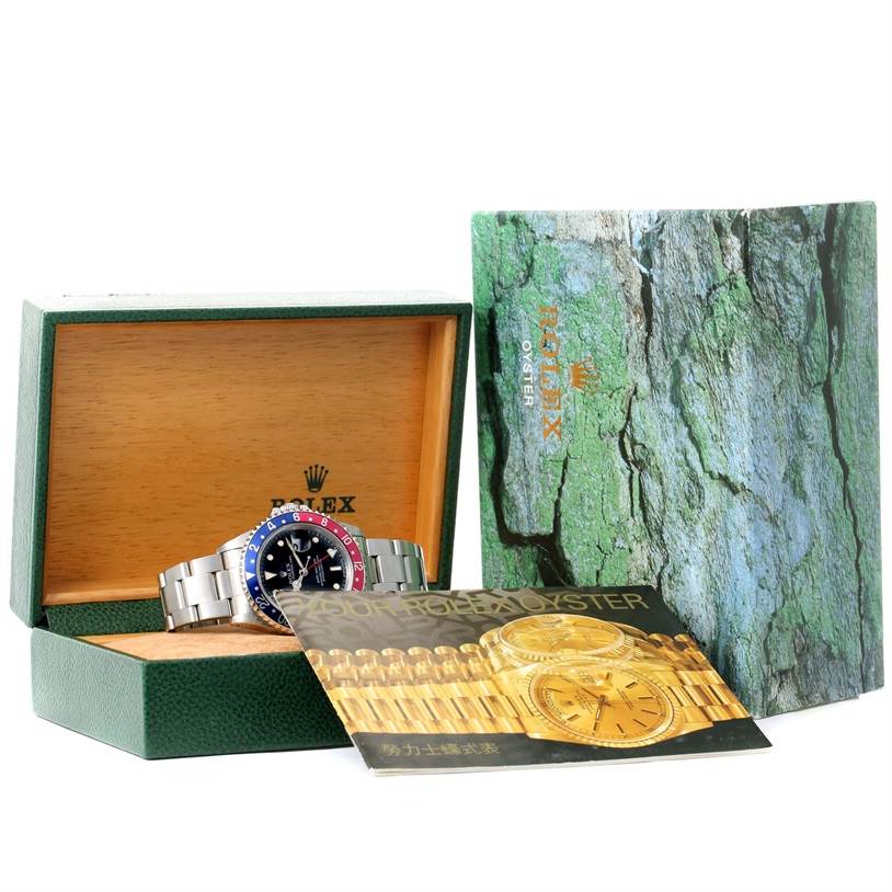 The Rolex GMT-Master 16700 Men's Stainless Steel Black Dial 16700 Men's Stainless Steel Black Dial watch is displayed in an open green box with accompanying booklets.