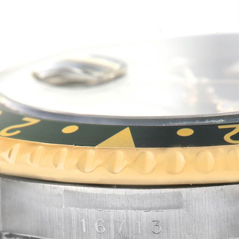 This close-up image of a Rolex GMT-Master 16713 Men's Stainless Steel Black Dial 16713 Men's Stainless Steel Black Dial watch shows the bezel, crystal, and part of the case with the model number 16713.