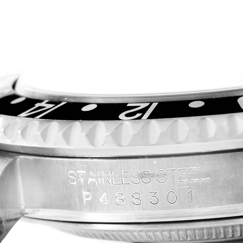 This close-up image of the Rolex GMT-Master 16710 Men's Stainless Steel Black Dial 16710 Men's Stainless Steel Black Dial watch shows the bezel, part of the case, and engraved serial number.