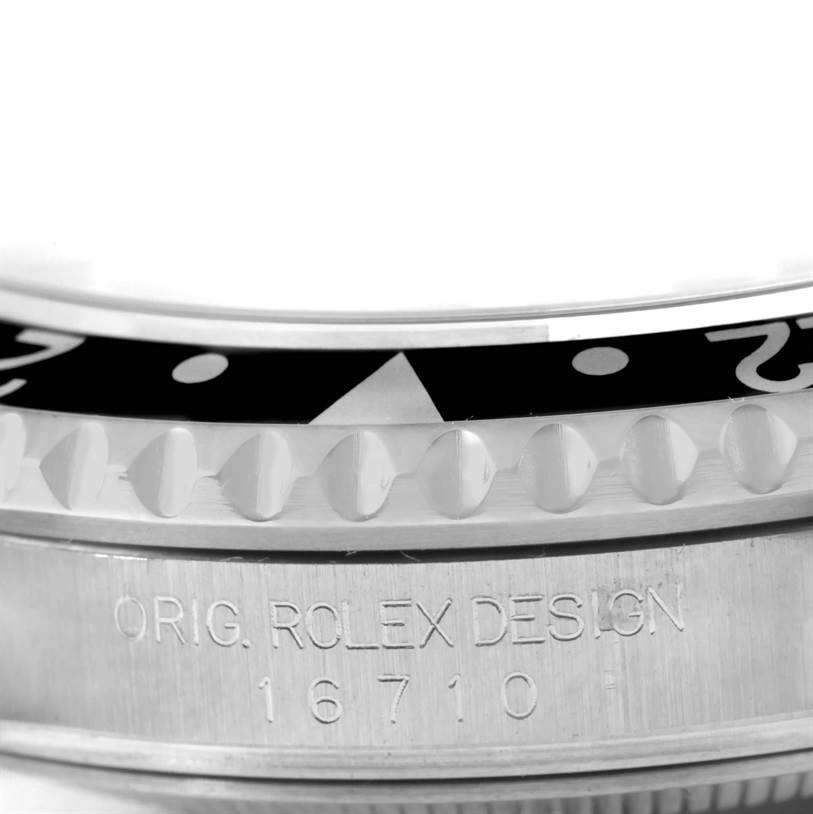 Close-up angle of the bezel and case of a Rolex GMT-Master 16710 Men's Stainless Steel Black Dial 16710 Men's Stainless Steel Black Dial watch, model 16710, showing the engraved "ORIG. ROLEX DESIGN".