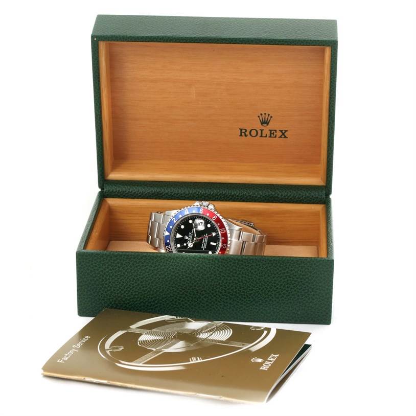 The Rolex GMT-Master 16710 Men's Stainless Steel Black Dial 16710 Men's Stainless Steel Black Dial watch is presented in an open green and wood box with a booklet placed in front.