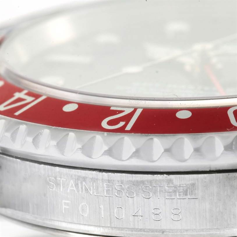 This close-up angle of the Rolex GMT-Master 16710 Men's Stainless Steel Black Dial 16710 Men's Stainless Steel Black Dial watch shows the bezel, case, and engraved serial number on the stainless steel.