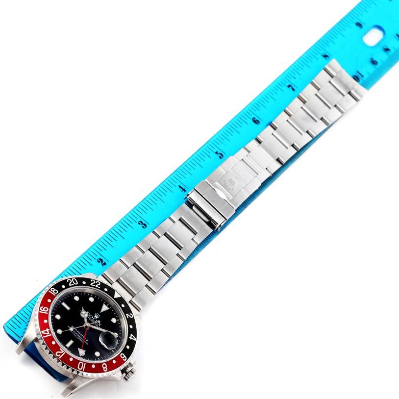 The image shows a bird's-eye view of a Rolex GMT-Master 16710 Men's Stainless Steel Black Dial 16710 Men's Stainless Steel Black Dial watch, highlighting the face, bezel, and metal bracelet alongside a blue ruler.