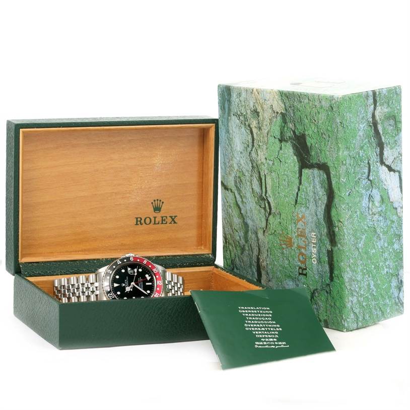 The Rolex GMT-Master 16710 Men's Stainless Steel Black Dial 16710 Men's Stainless Steel Black Dial watch is shown in its open box, with adjacent packaging and a booklet.