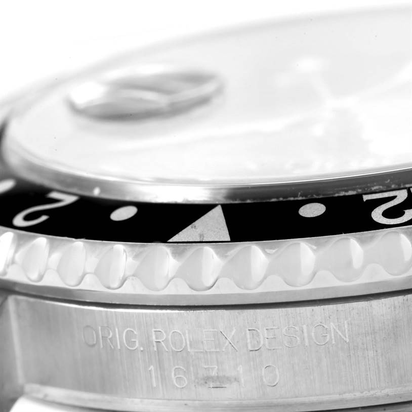 This image shows an angled close-up of the bezel and case of the Rolex GMT-Master 16710 Men's Stainless Steel Black Dial 16710 Men's Stainless Steel Black Dial model with "ORIG. ROLEX DESIGN 16710" engraved.