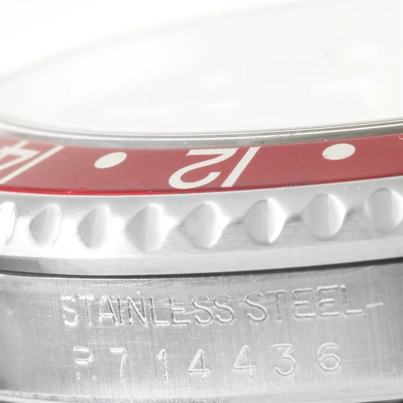 This close-up image of a Rolex GMT-Master 16710 Men's Stainless Steel Black Dial 16710 Men's Stainless Steel Black Dial watch shows the edge of the bezel, part of the dial, and engraved text on the stainless steel case.