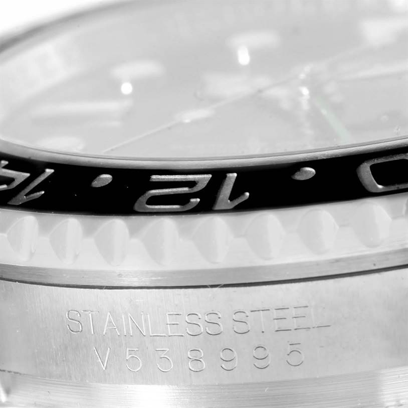 This close-up image of a Rolex GMT-Master 116710BKSO Men's Stainless Steel Black Dial 116710BKSO Men's Stainless Steel Black Dial watch focuses on the bezel and serial number on the stainless steel case.