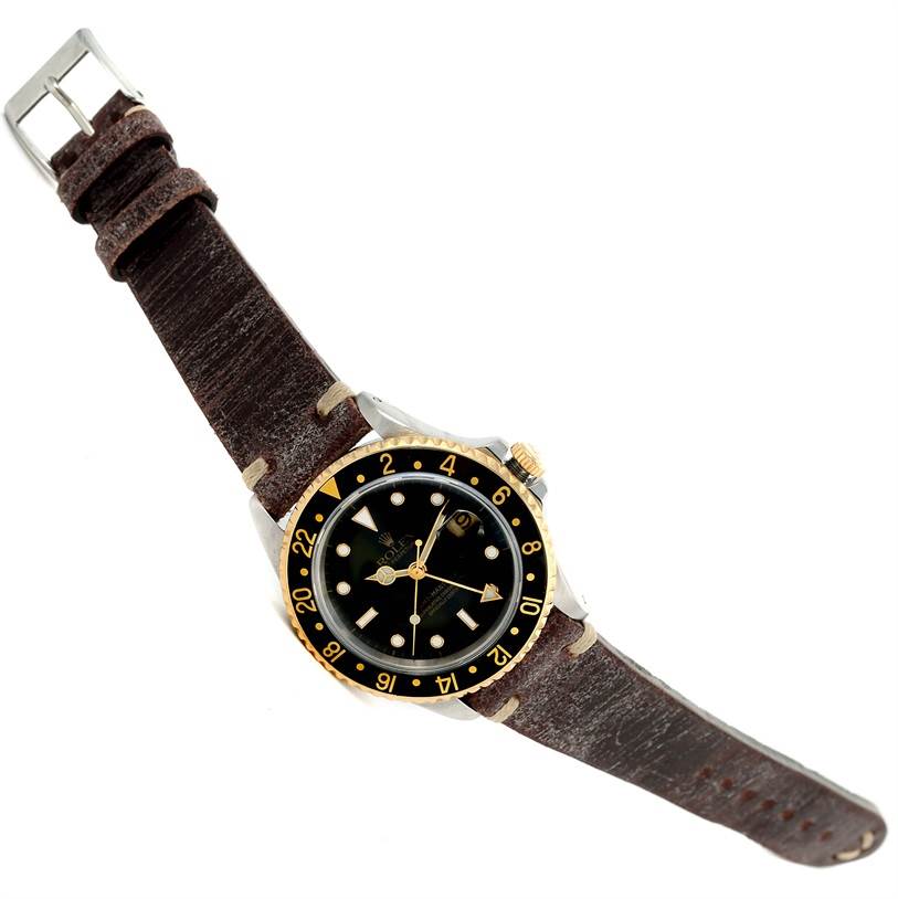 The image shows a top-down angled view of a Rolex GMT-Master 16713 Men's Stainless Steel Black Dial 16713 Men's Stainless Steel Black Dial watch with its dial, bezel, and leather strap visible.