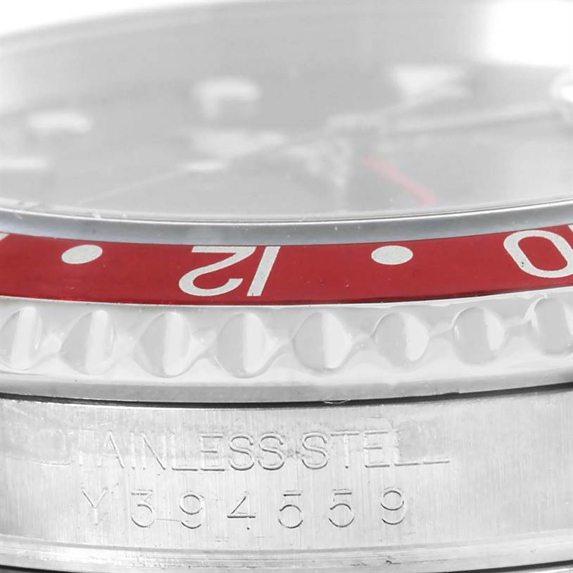 The image shows a close-up of the Rolex GMT-Master 16710 Men's Stainless Steel Black Dial 16710 Men's Stainless Steel Black Dial's bezel and part of the stainless steel case with engraved numbers.