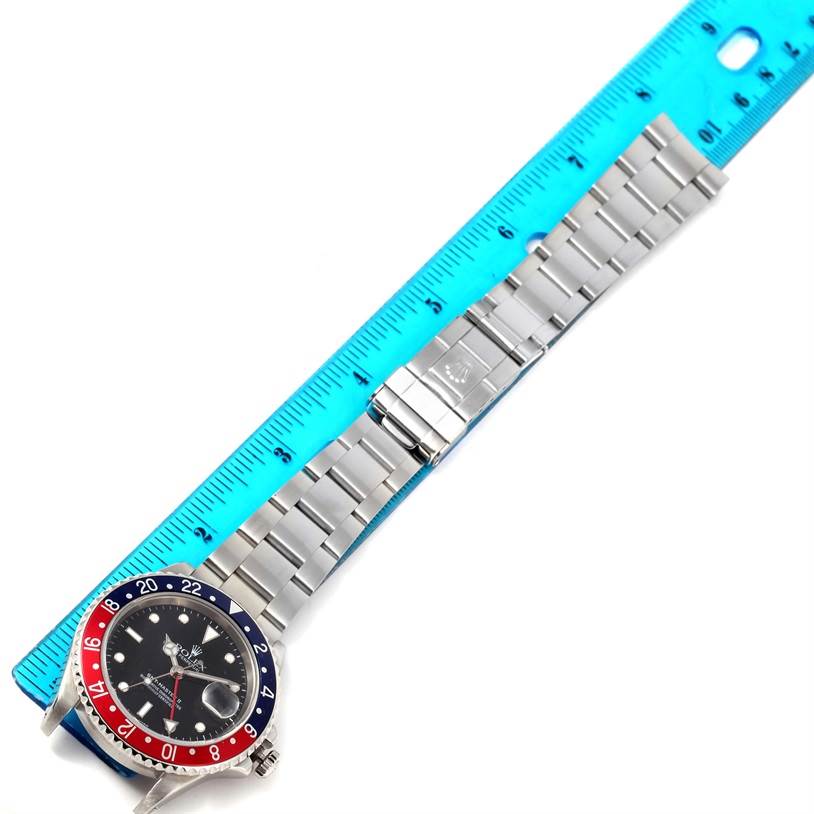 The image shows a Rolex GMT-Master 16710 Men's Stainless Steel Black Dial 16710 Men's Stainless Steel Black Dial watch laid flat with a view of its dial, bezel, bracelet, and clasp, next to a ruler.