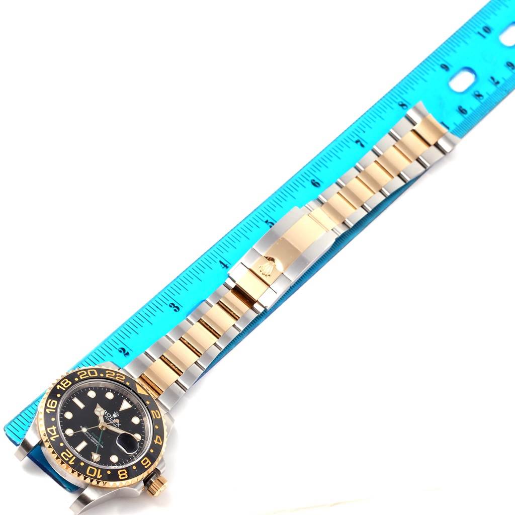 The image shows a Rolex GMT-Master 116713 Men's Stainless Steel Black Dial 116713 Men's Stainless Steel Black Dial watch laid next to a blue ruler, displaying its face and entire bracelet.