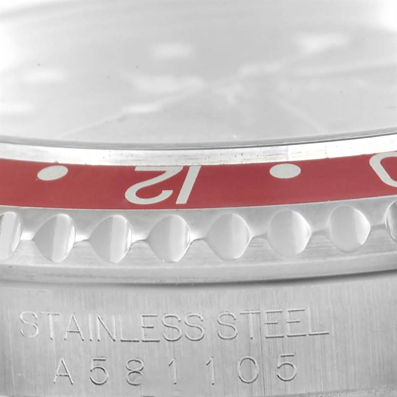 This close-up image of a Rolex GMT-Master 16700 Men's Stainless Steel Black Dial 16700 Men's Stainless Steel Black Dial watch shows the bezel, part of the dial, and serial number engraved on the case.