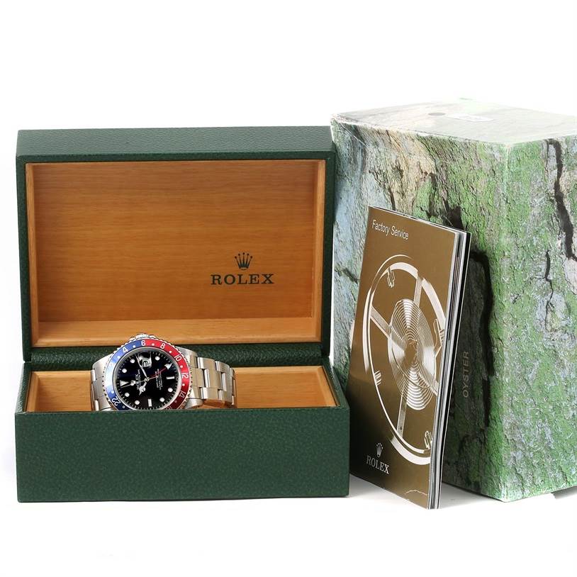 The Rolex GMT-Master 16700 Men's Stainless Steel Black Dial 16700 Men's Stainless Steel Black Dial watch is displayed inside its opened box, with manuals and packaging visible on the side.