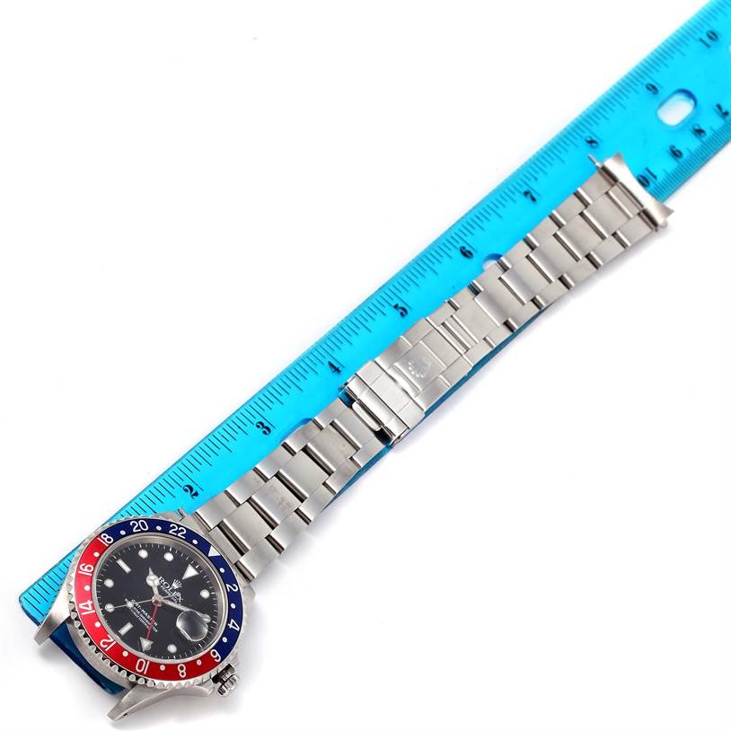 The image shows a Rolex GMT-Master 16700 Men's Stainless Steel Black Dial 16700 Men's Stainless Steel Black Dial watch laying flat with a blue ruler beside it, measuring the length of the watch and bracelet.
