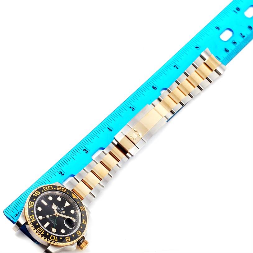 The image shows a Rolex GMT-Master 116713 Men's Stainless Steel Black Dial 116713 Men's Stainless Steel Black Dial watch laid flat against a blue ruler, highlighting its band and face.