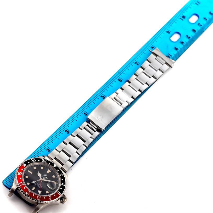 The Rolex GMT-Master 16700 Men
s Stainless Steel Black Dial 16700 Men
s Stainless Steel Black Dial watch is shown laid out flat with its bracelet and clasp fully visible, alongside a blue ruler for scale.