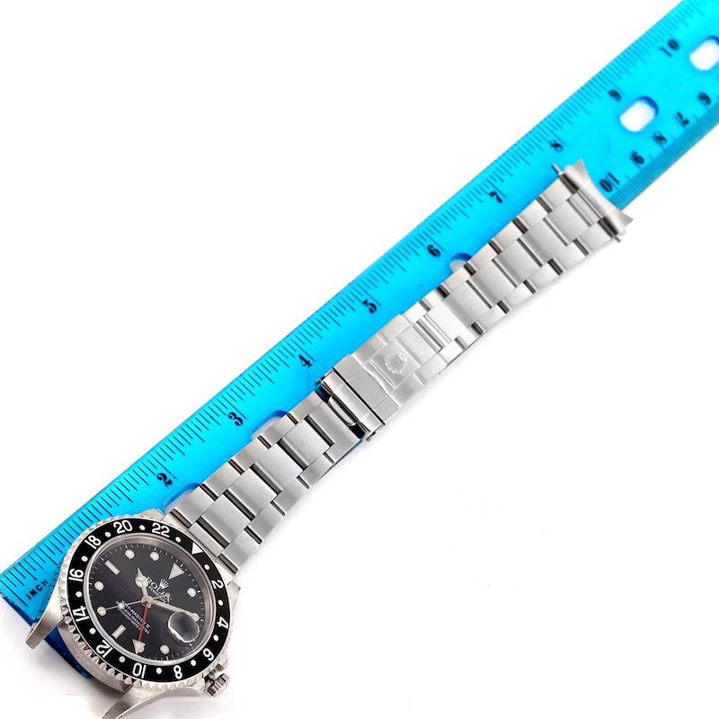 The image shows a Rolex GMT-Master 16710 Men's Stainless Steel Black Dial 16710 Men's Stainless Steel Black Dial watch with a stainless steel bracelet laid next to a blue ruler at a slight diagonal angle.