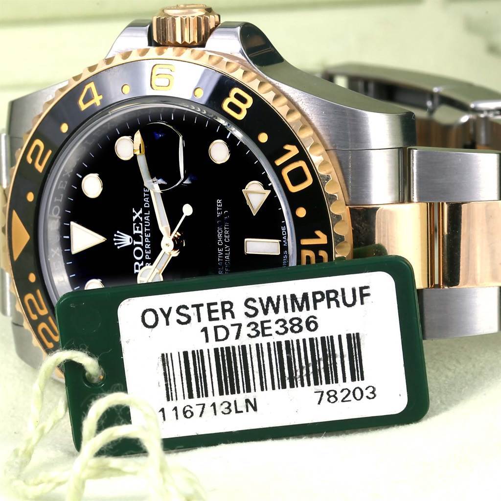 The image shows a close-up of the Rolex GMT-Master 116713 Men's Stainless Steel Black Dial 116713 Men's Stainless Steel Black Dial watch's face, bezel, and part of its bracelet, with an Oyster Swimpruf tag.