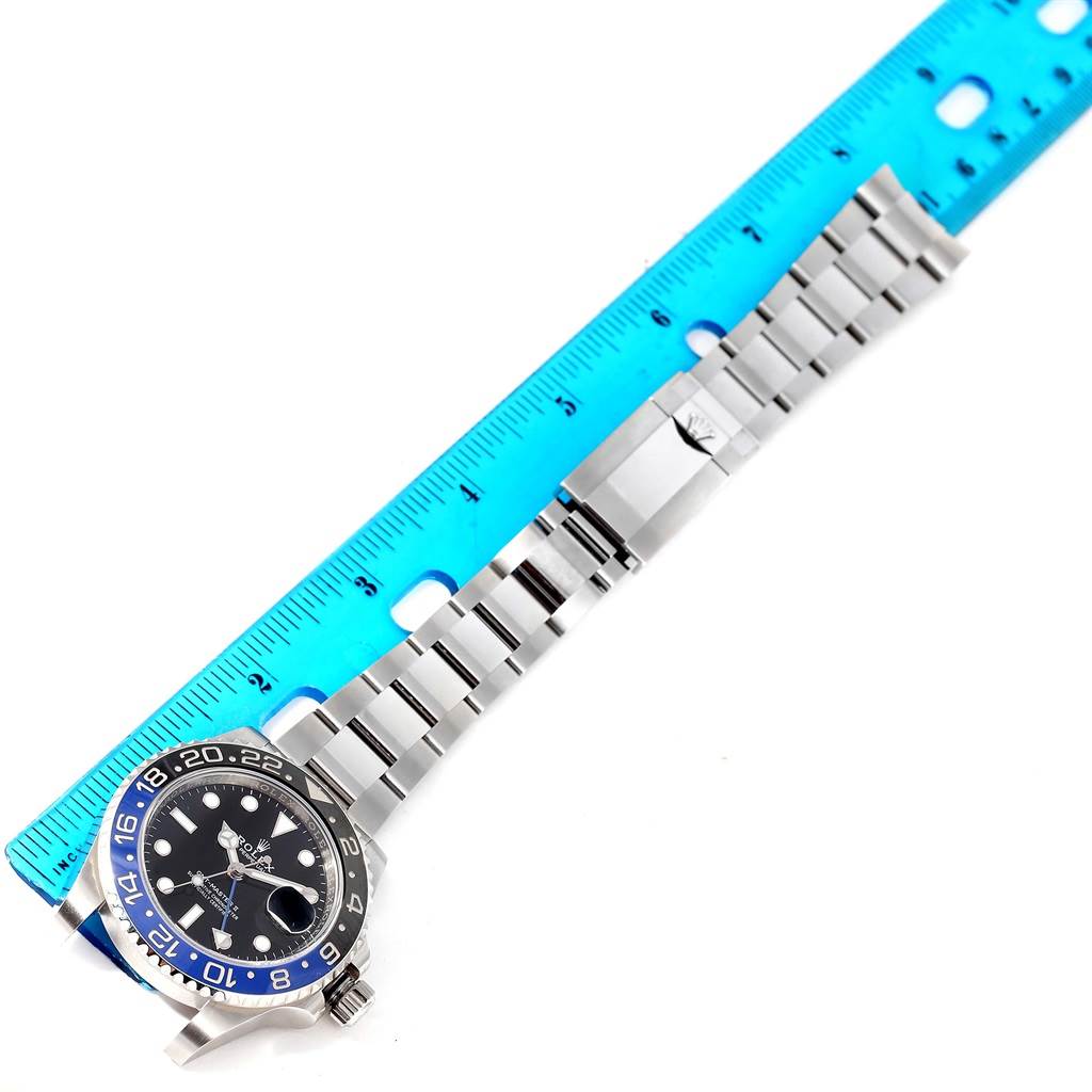 This image shows a top-down view of a Rolex GMT-Master 116710BLNR Men's Stainless Steel Black Dial 116710BLNR Men's Stainless Steel Black Dial watch, displaying its bezel, dial, and bracelet alongside a blue ruler.