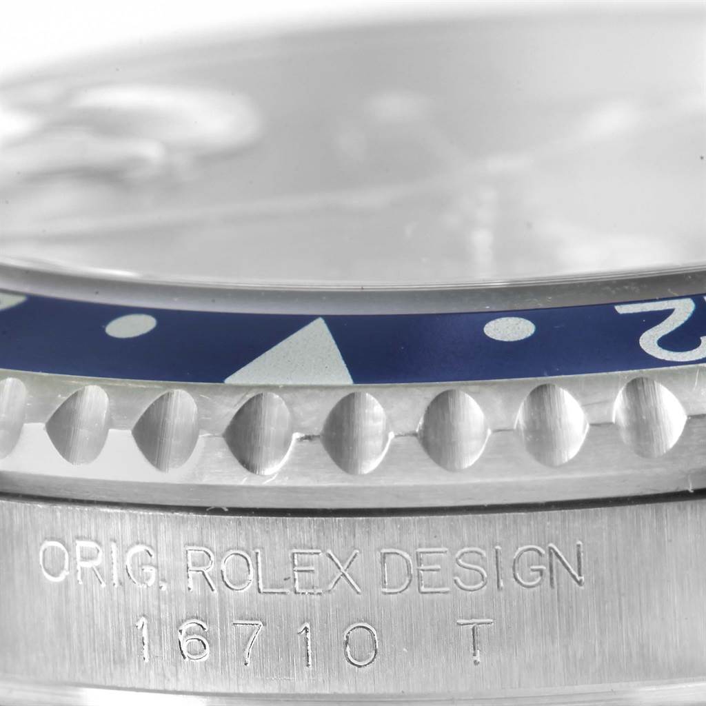 This close-up image of a Rolex GMT-Master 16710 Men's Stainless Steel Black Dial 16710 Men's Stainless Steel Black Dial watch shows the bezel and engraved model number 16710 T.