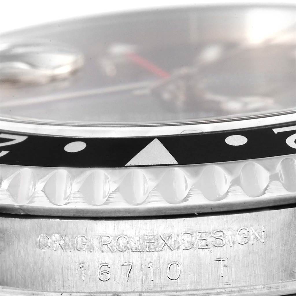 This close-up of a Rolex GMT-Master 16710 Men's Stainless Steel Black Dial 16710 Men's Stainless Steel Black Dial watch shows the bezel, part of the dial, and the model number "16710 T".